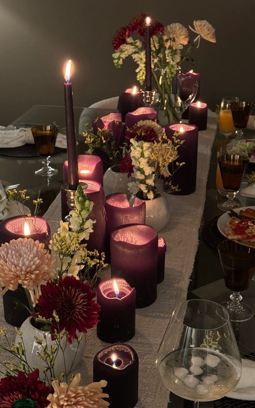 Une table dressée avec des bougies prune et des fleurs