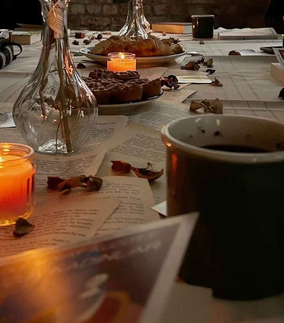 Une table de lecture avec bougies, fleurs, pâtisseries et pages de livres